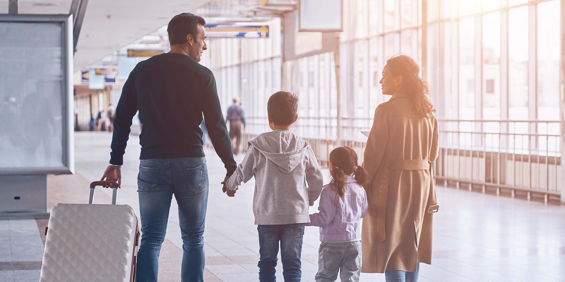 Full length rear view of family with two little kids walking by